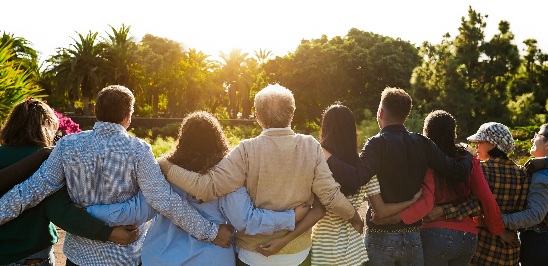 Group of adults standing outdoors with arms around each other.